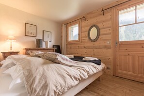 Slaapkamer met houten lambrisering, een bed, nachtkastje met lamp, spiegel en ingelijste foto's aan de muur.