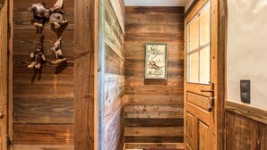 Un pasillo de madera con una puerta de madera, un letrero en la pared y una alfombra roja.
