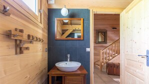 Ein Holzinterieur mit Waschbecken, Spiegel und Gardehaken.