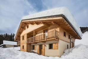Un chalet en bois doté d’un balcon, entouré de neige.