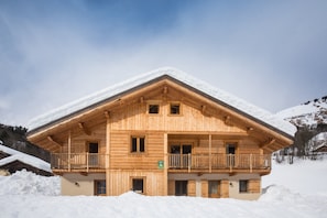 Un chalet in legno con un balcone, immerso nella neve.