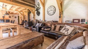 Ein rustikales Interieur mit einem Holzesstisch, einem Ledersofa und einer großen Wanduhr.