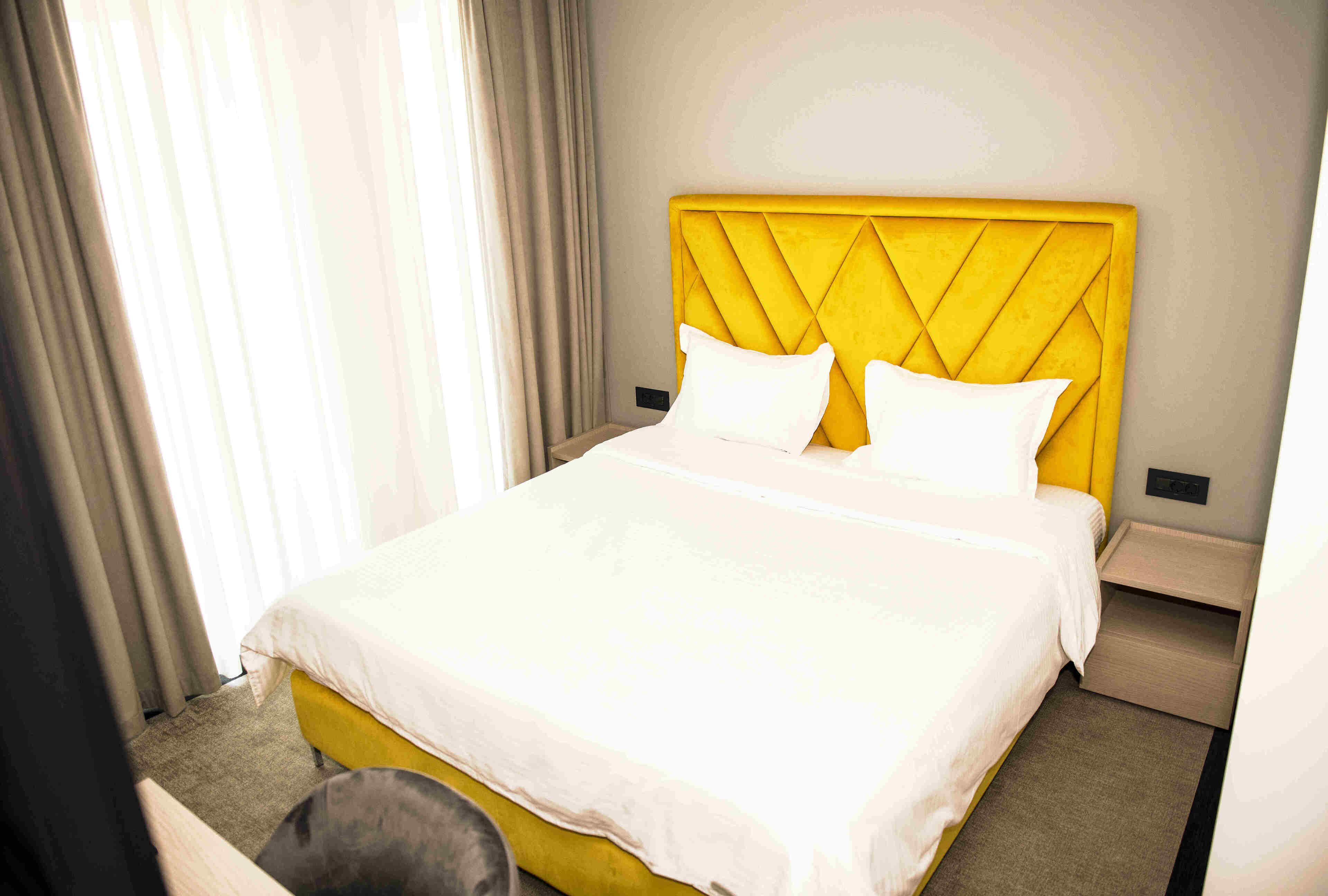 A hotel room with a bed, a nightstand, and a chair.