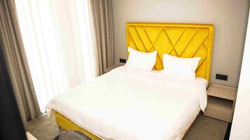 A hotel room with a bed, a nightstand, and a chair.