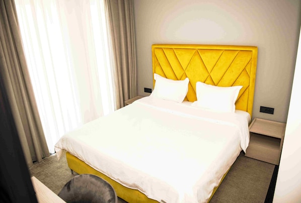 Una habitación de hotel con cama, mesita de noche y silla.