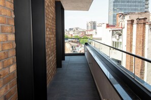 Un estrecho pasillo con paredes de ladrillo y barandilla de vidrio con vistas a un paisaje urbano.