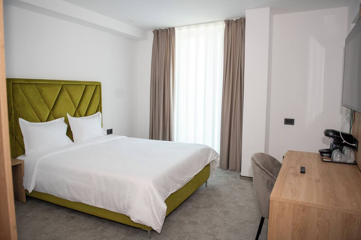 A hotel room with a bed, a desk, and a television.