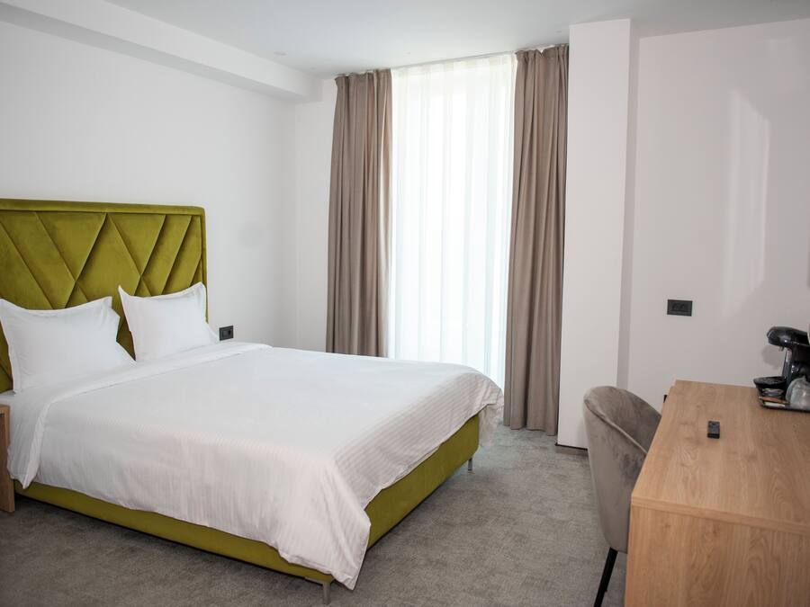A hotel room with a bed, a desk, and a television.