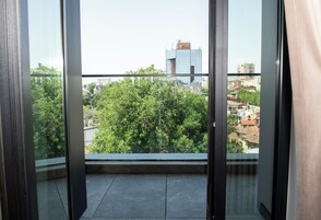Un balcón con vistas a la ciudad, que incluye edificios y árboles.