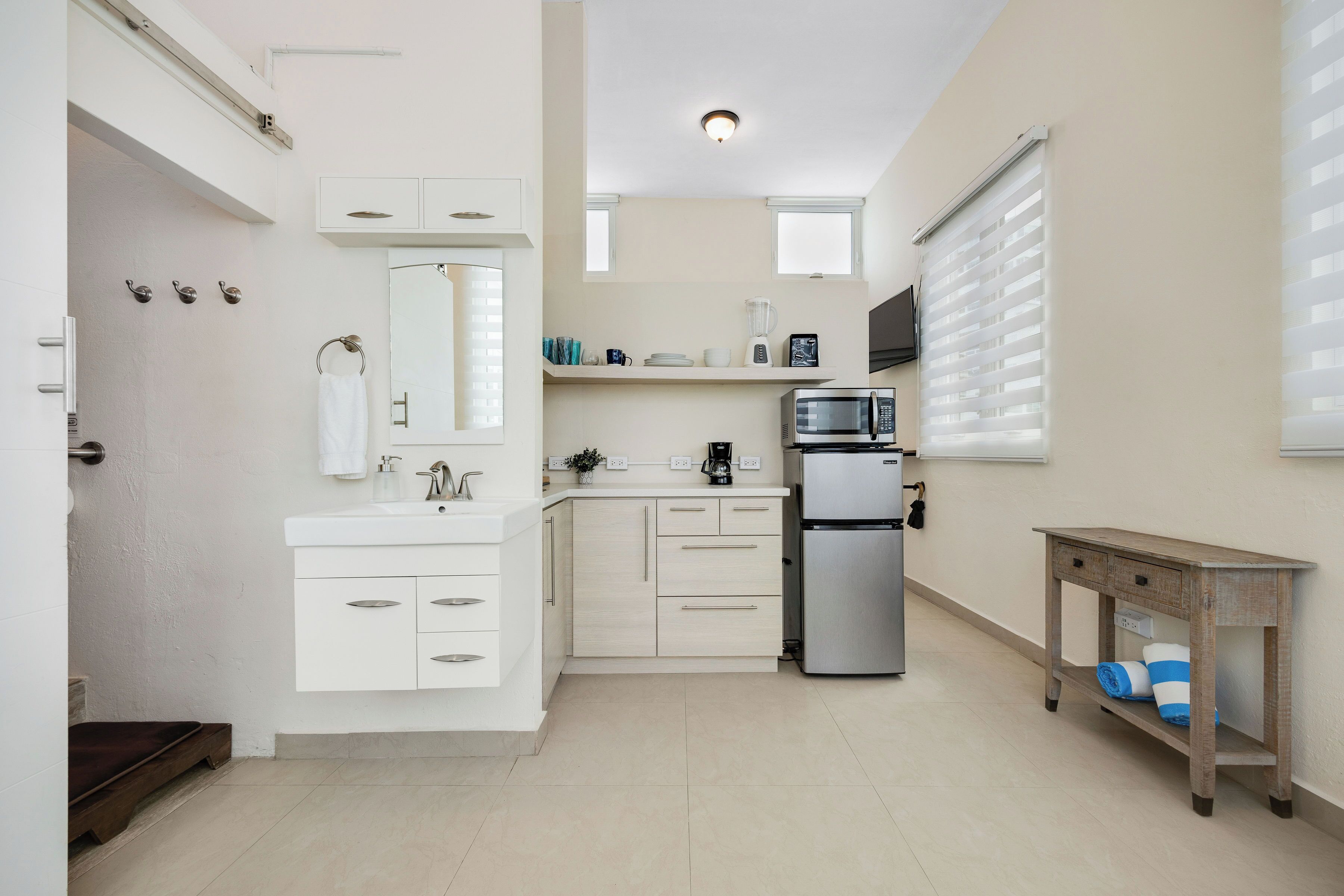 Een moderne keuken met witte kastjes, een ingebouwde magnetron en een klein houten tafeltje.
