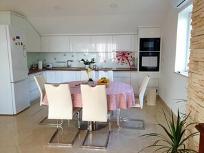 Cozy kitchen with a central island, sink, and toaster, perfect for meal preparation. A dining table with four chairs and a potted plant complete the space.