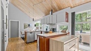 A modern kitchen with a wooden ceiling, large windows, and a view of the outdoors. - Cozy home in Hasle with sauna (Hasle)