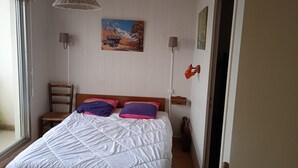 Een slaapkamer met een bed, een raam, een schilderij en een lamp.