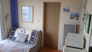 Een slaapkamer met een bed, een deur, een wandairconditioner en een raam met uitzicht op een gebouw.