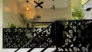 A staircase with black railings and white tiles, leading to a landing with ceiling fans and potted plants. - Patio Paradise, Pitampura
Cozy and peaceful 3BHK Condo (New delhi)
