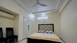 A bedroom with a bed, a ceiling fan, a wardrobe, and two chairs. - Patio Paradise, Pitampura
Cozy and peaceful 3BHK Condo (New delhi)