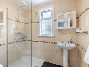 Un baño con ducha de vidrio, bañera, lavamanos y ventana.