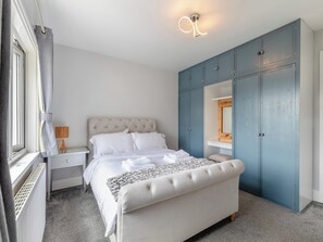 Un dormitorio con cama, mesita de noche, cómoda, espejo y armario.