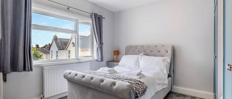 A bedroom with a bed, a window, a radiator, and a light fixture.