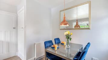 A dining area with a table, chairs, a vase with flowers, and a pendant light.