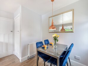 A dining area with a table, chairs, a vase with flowers, and a pendant light. - 1 bedroom accommodation in Torquay (Torquay)