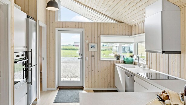 Eine moderne Küche mit Holzvertäfelung, einem großen Fenster und Edelstahlgeräten.