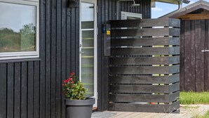 Ein modernes Gebäude mit dunkler Holzfassade, einer Glastür und einem großen Holztor.