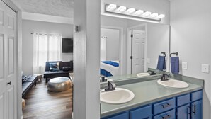 A modern bathroom with a large mirror, dual sinks, and a vanity with blue cabinets. - Stunning Condo Near Lake 2BR 2BA  right in Branson! Sleeps 6 .  (Branson)