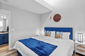 A modern bedroom with a large bed, a blue headboard, and a round wall decoration.