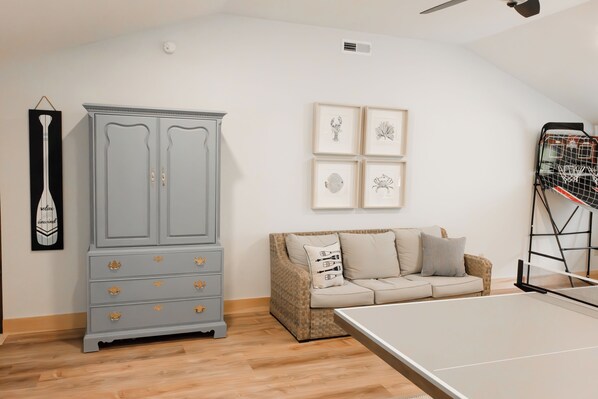 A room with a grey cabinet, a sofa, and a ping pong table.