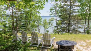 A lakeside view with Adirondack chairs and a metal table. - Designer Oceanfront, Views of Acadia National Park, Near Bar Harbor (Trenton)