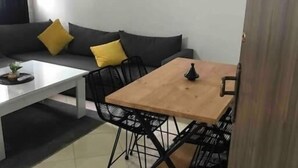 Ein kleiner, moderner Wohnraum mit einer Couch, einem Couchtisch und einem Esstisch mit Stühlen.