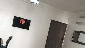 Ein Essbereich mit einem weißen Tisch, einem schwarzen Stuhl, einer Pendelleuchte, einem gerahmten Bild an der Wand und einer Tür.