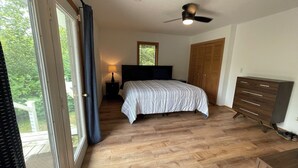 Una camera da letto con un letto, un comodino, una cassettiera, una ventola a soffitto e una finestra con tende.