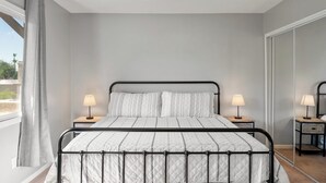 A bedroom with a bed, two bedside tables with lamps, a ceiling fan, and a large window with curtains. - Ideal Old Town Scottsdale Location! Perfect for Families. Camelback Mt. View! (Scottsdale)