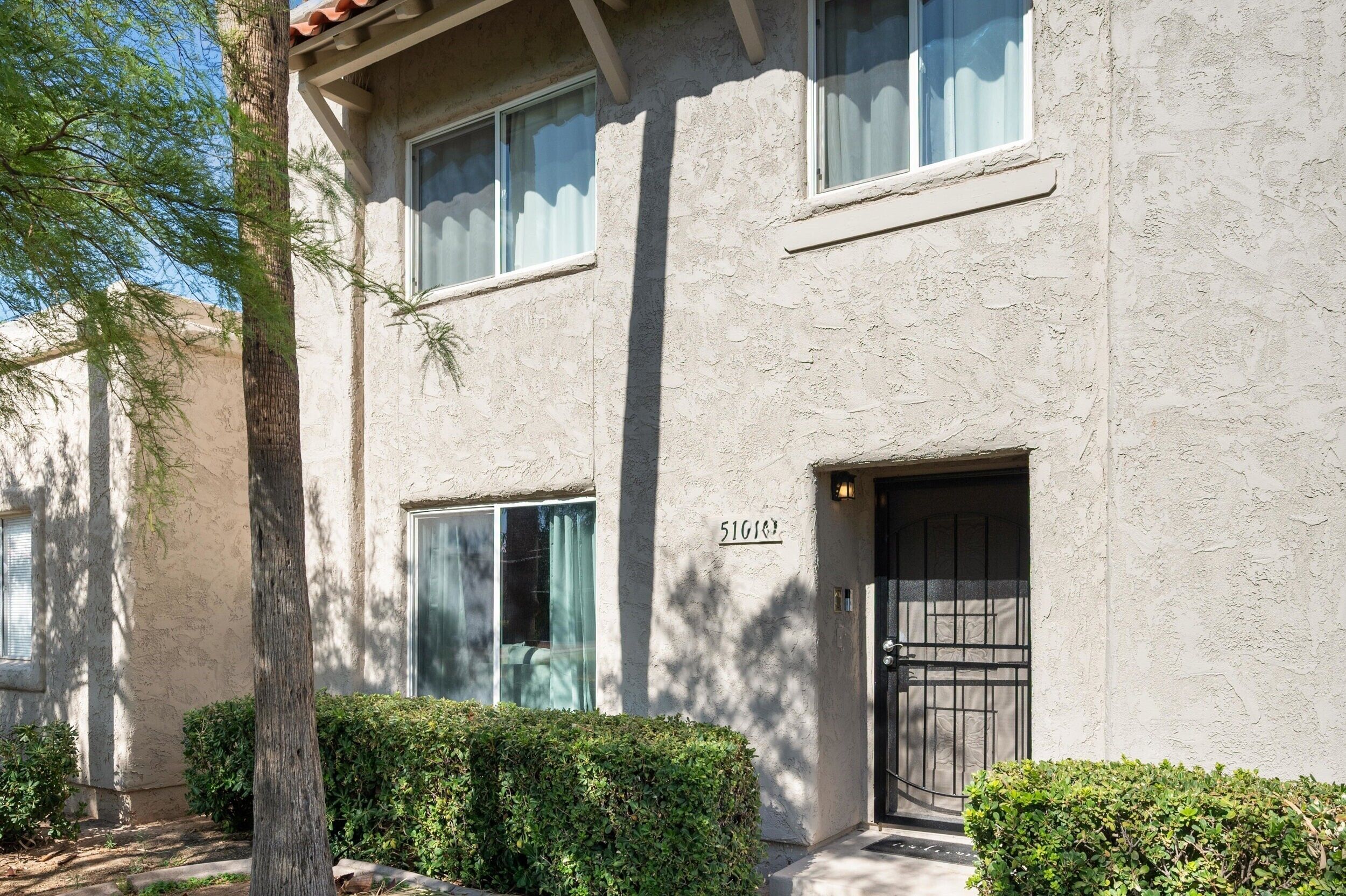 A two-story building with a textured facade, a number '51601' on the wall, and a black gate at the entrance.