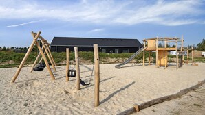 Platja sorrenca amb jocs de fusta, incloent balanços i tobogan.