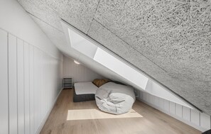 A compact attic bedroom with a sloped ceiling, a built-in bed, and a skylight. - Lovely home in Rømø with sauna (Rømø)