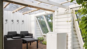 A covered outdoor seating area with wicker furniture, a small table, and a white refrigerator. - Nice home in Harboøre with WiFi (Harboøre)