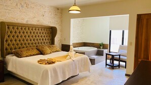 Une chambre dotée d’un grand lit, d’une baignoire intégrée et d’un coin salon.