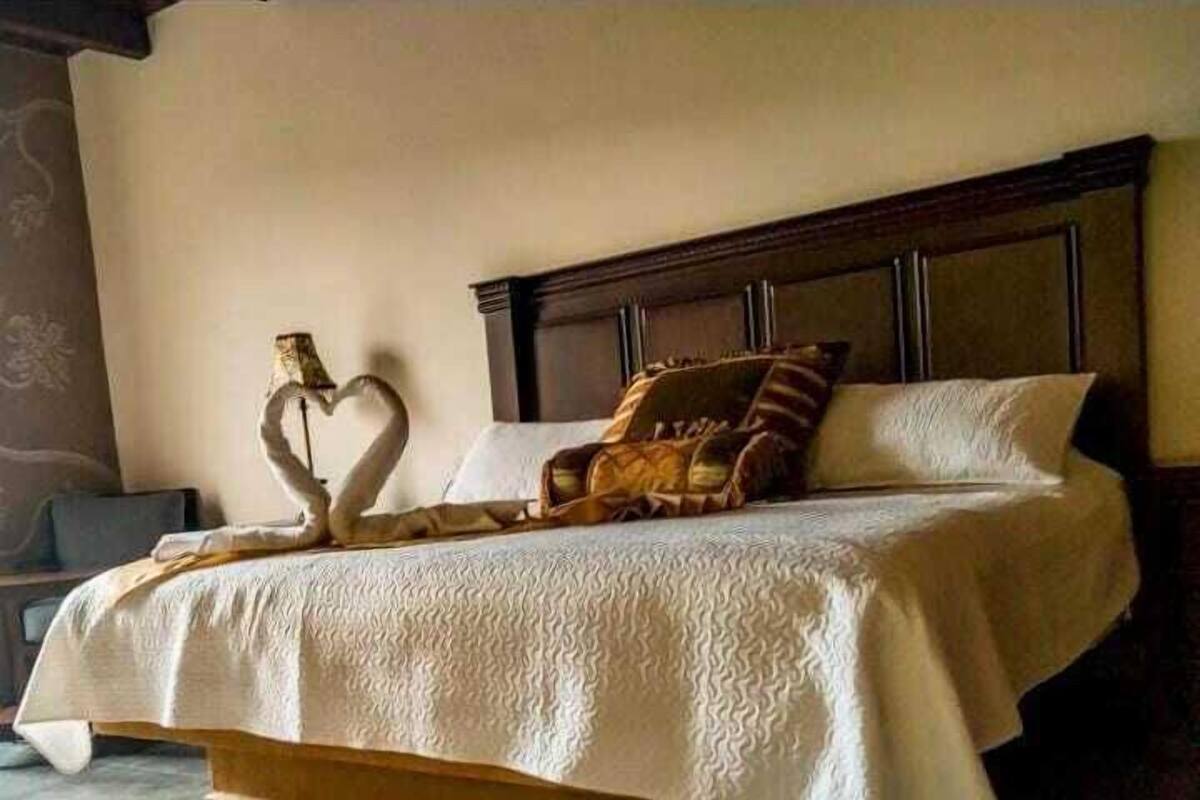 Una cama con una decoración en forma de corazón, cabecera de madera y colcha estampada.