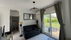 A modern living room with a black sofa, a floor lamp, and a large window with curtains.