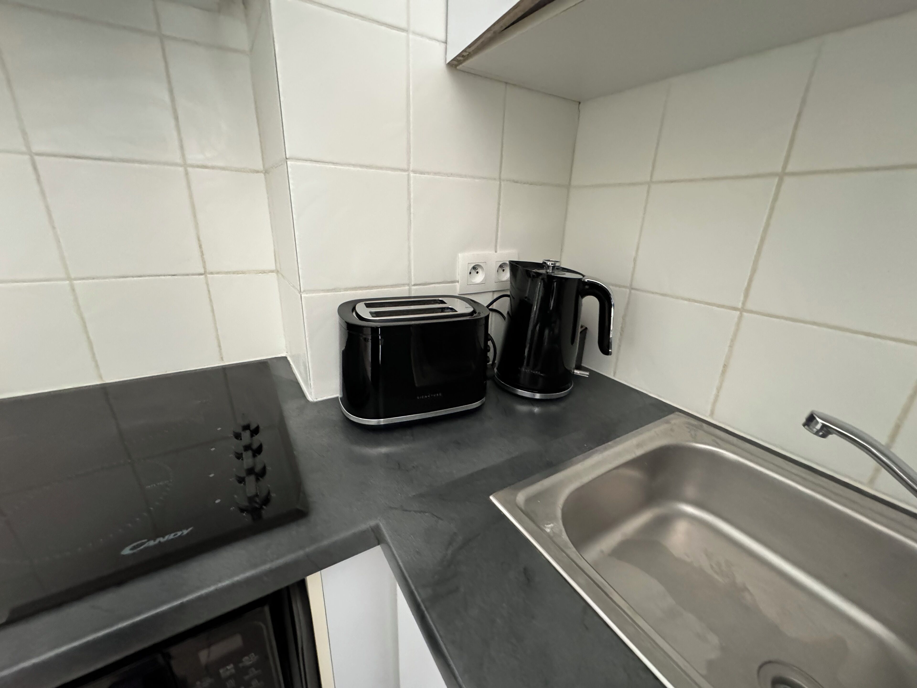 Een keuken met een broodrooster, een koffiezetapparaat en een spoelbak.