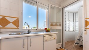 A kitchen with a sink, a dishwasher, and a window with a view of buildings. - MalagaSuite Costa Sol Oasis 3 (Torremolinos)