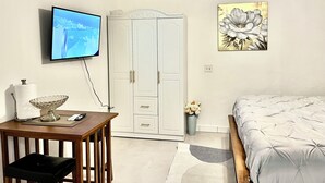 Un dormitorio con cama, televisor montado en la pared, armario y ventilador de techo.