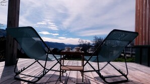 A wooden deck with two green folding chairs and a small table, overlooking a mountainous landscape. - L'alticime - LA Feclaz LES Deserts (LA FECLAZ LES DESERTS)