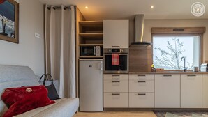 A compact kitchen with a refrigerator, microwave, oven, and a stainless steel range hood. - L'alticime - LA Feclaz LES Deserts (LA FECLAZ LES DESERTS)