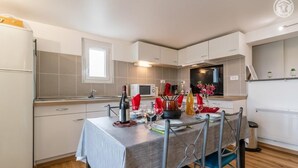 A compact kitchen with a dining table set for two, a microwave, and a refrigerator. - LA Marmotte - Saint Beron (SAINT BERON)