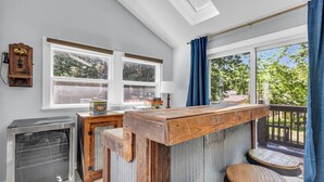 A kitchen with a wooden bar counter, two windows, a built-in oven, and a view of the outdoors. - Spacious Home! Game Room, Swing Set, Deck, Yard, Outdoor Fun + Sleeps 16 (Merriam)