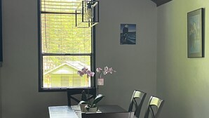 A dining area with a large window, a table, chairs, and a bench. - Modern Alderbrook pet-friendly retreat.   (Union)